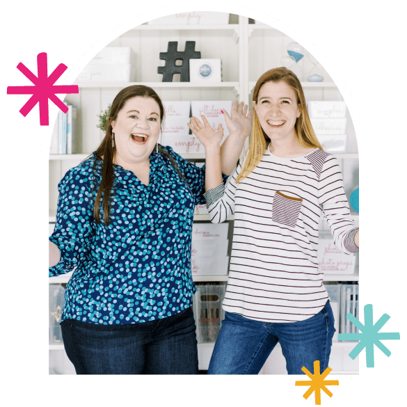 Laura and Tasha excitedly smiling and standing in an organized office